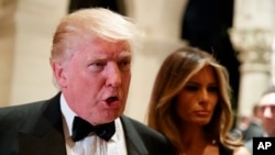 Melania Trump, right, looks on as her husband President-elect Donald Trump talks to reporters during a New Year's Eve party at Mar-a-Lago, Dec. 31, 2016, in Palm Beach, Florida. On Tuesday, Trump criticized the largest U.S. automaker for sending its Mexican-made Chevrolet Cruze compact models back to U.S. car dealers tax free.