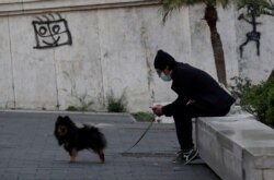 A man wearing a mask sits with his dog as Italy remains under a nationwide lockdown in a government decree that orders Italians to stay at home, Naples, Italy, March 19, 2020.