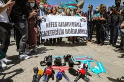 Reporting equipment lies on the ground outside the offices of Ankara’s government, and protesters hold a banner that reads "We can’t breathe. Journalism cannot be drowned” during a rally for journalists to be protected from police, June 29, 2021.