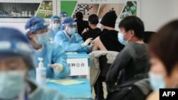 Des gens reçoivent des vaccins contre le coronavirus Covid-19 dans un centre de vaccination temporaire à Pékin le 8 janvier 2021. (Photo de STR / CNS / AFP) / China OUT