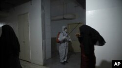 FILE - A member of a humanitarian aid agency disinfects inside Ibn Sina Hospital as prevention against the coronavirus in Idlib, Syria, March 19, 2020.