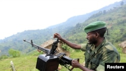 A M23 rebel fighter prepares his machine gun at their defense position in Karambi, eastern Democratic Republic of Congo (DRC) in north Kivu province, near the border with Uganda, July 12, 2012. 