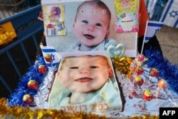 FILE - A supporter holds a cake with pictures of Kfir Bibas, the youngest hostage to be kidnapped by Hamas militants on the October 7 attack together with his mother and brother, at his first birthday celebration in Tel Aviv, on January 18, 2024.