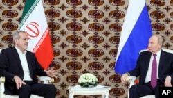 Russian President Vladimir Putin, right, and Iranian President Masoud Pezeshkian, shake hands during their meeting on the sidelines of an international forum in Ashgabat, Turkmenistan, Oct. 11, 2024. (Sputnik, Kremlin pool photo via AP)