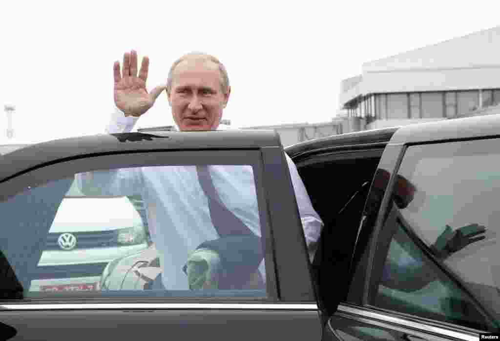 Russian President Vladimir Putin waves as he gets into a car upon his arrival at an airport outside Minsk, Aug. 26, 2014.