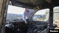 FILE - A Palestinian checks a car burned in an Israeli settlers raid near Salfit in the Israeli-occupied West Bank, Dec. 3, 2023. 