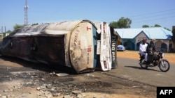 Two people ride past what remains of a fuel tanker whose explosion killed more than 140 people in Majiya, Nigeria, Oct. 16, 2024.