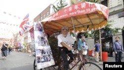 Chen Guanming, yang naik becak dari Tiongkok ke London, berpose di daerah pecinan London. (Foto: Reuters)