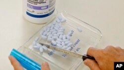 FILE- A pharmacy tech poses for a picture with pills of the generic version of Vicodin, in Edmond, Okla. The U.S. Centers for Disease Control and Prevention says not only do pain medications run a high risk of addicting the user, but they can actually make patients' chronic pain worse. 