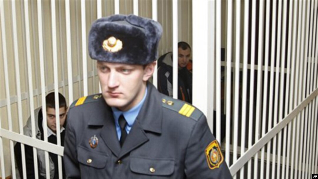 Russian citizens Artyom Breus, behind right, and Ivan Gaponov, left, sit in a cage during a court session in Minsk, Belarus, February 22, 2011 - Breus and Gaponov were detained in Minsk on December 19, 2010, during an unsanctioned rally in support of oppo