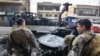 Lebanese soldiers stand guard as a crane removes the wreckage of a vehicle at the site of an Israeli drone attack in Aaraiya, east of Beirut, on November 7, 2024, amid the ongoing war between Israel and Hezbollah.