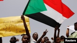 Les manifestants agitent des drapeaux soudanais, tiennent des banderoles et scandent des slogans lors d'une manifestation devant le ministère de la Défense à Khartoum, au Soudan, le 18 avril 2019. 