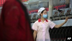 (FILE) A worker checks machines processing cotton yarn at a Huafu Fashion plant in Aksu in western China's Xinjiang Uyghur Autonomous Region, Tuesday, April 20, 2021. 