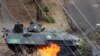 Tentara Nasional Venezuela mengamati api di bawah tank mereka, yang dipicu oleh bom Molotov dalam sebuah protes melawan pemerintahan Presiden Nicolas Maduro di San Cristobal, sekitar 660 km barat daya ibukota Caracas (27/2).