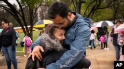 FILE - An Afghan man is wrapped in a bear hug by his daughter as he picks up his children from school, in Alexandria, Virginia, April 7, 2022. The family was evacuated from Afghanistan and is trying to make a new life in the U.S., while in immigration limbo.