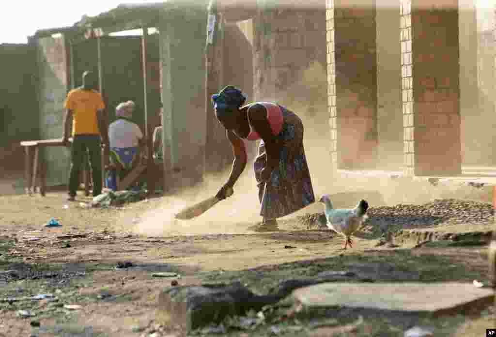 A woman sweeps outside her house in Lusaka, Zambia, Aug. 14, 2021.