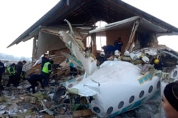 In this handout photo provided by the Emergency Situations Ministry of the Republic of Kazakhstan, police and rescuers work on the side of a plane crash near Almaty International Airport, outside Almaty, Kazakhstan, Dec. 27, 2019.