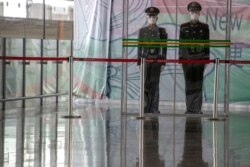 Chinese paramilitary policemen stand on duty behind a barrier at the Capital International Airport terminal 3 in Beijing, March 12, 2020.
