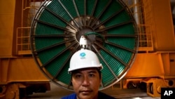 FILE - In this photo taken on Oct. 22, 2010, Laotian worker Phoumgeumh Chanthasone stands watch inside the power station of the Nam Theun 2 dam project near Mahaxaitai, Laos.