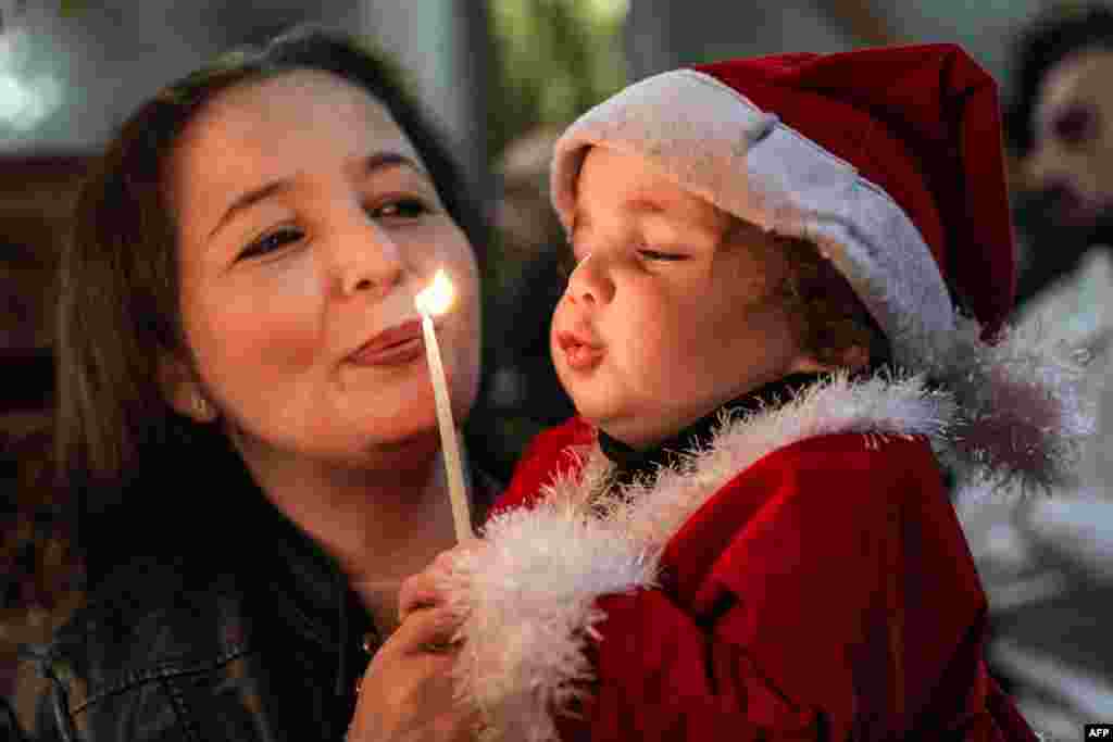 A child blows a candle during the Christmas morning service at the Greek Orthodox Church of Saint Porphyrius in Gaza City.