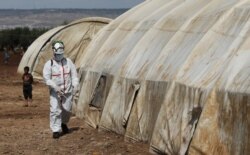 A member of the Syrian civil defense sanitizes a tent at the Bab al-Nour internally displaced persons camp, to prevent the spread of COVID-19 in Azaz, Syria, March 26, 2020.