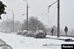 Investigators work next to damaged cars at a site of a Russian missile strike in Zaporizhzhia, Ukraine, Jan. 8, 2024