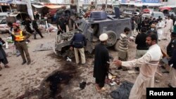 Petugas keamanan dan penyelematan mengumpulkan bukti di tempat ledakan bom di luar kota Peshawar (14/3). (Reuters/Fayaz Aziz)