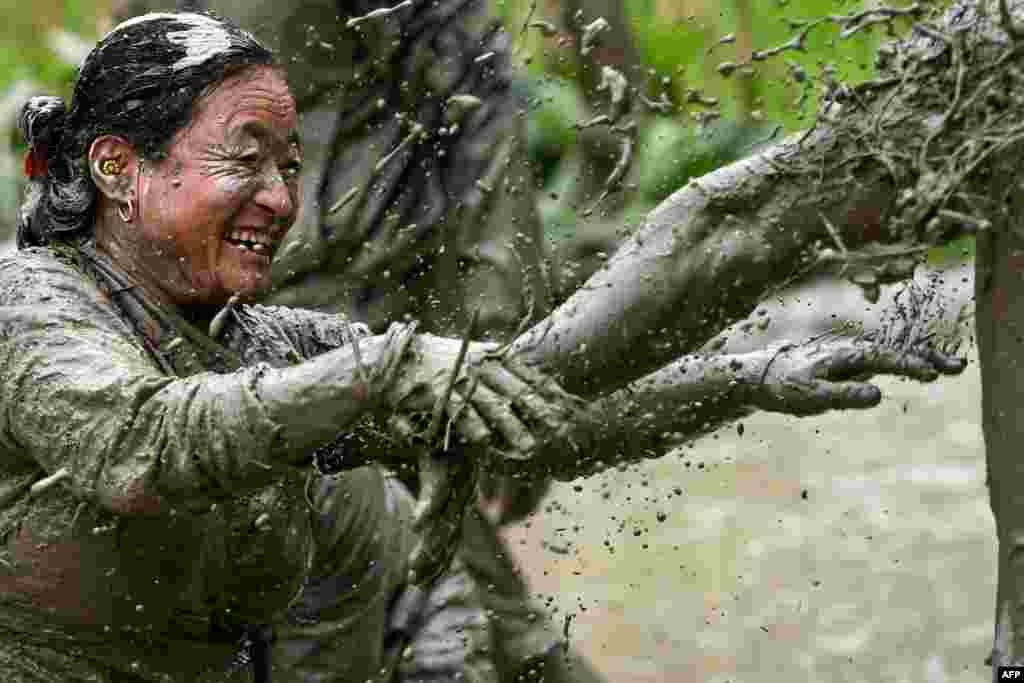 Mud-covered farmers play in a rice paddy field during &quot;National Paddy Day&quot;, which marks the start of the annual rice planting season, in Tokha village on the outskirts of Kathmandu, Nepal.
