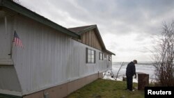 FILE - Tim Betts removes a horseshoe pit that he recently built at his family's beachfront home that is sitting off of its foundation in Washaway Beach, Washington.