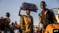South Sudanese returnees who have fled from the war in Sudan carry their belongings while arriving at a Transit Centre for refugees in Renk, on February 14, 2024.More than 550,000 people have now fled from the war in Sudan to South Sudan since the conflic