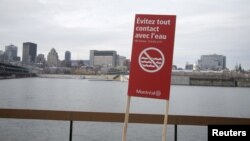A sign stating "Don't touch the water" is seen near the St. Lawrence river as the city of Montreal is seen in the background, Nov. 11, 2015. Montreal, Canada's second-largest city, began dumping untreated sewage into the St. Lawrence River on Wednesday.