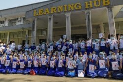 Teachers from Yangon University of Education wear red ribbons and pose with a three-finger salute as they take part in demonstration against the military coup in Yangon, Myanmar, Feb. 5, 2021.