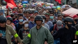 Pro-democracy protest leaders lock hands as they approach a police barricade during a street march in Bangkok, Thailand, Oct. 14, 2020. 