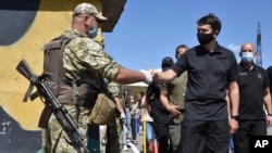 FILE - Ukraine's parliament speaker Dmytro Razumkov, right, greets a soldier at a checkpoint in Mayorsk, Donetsk region, Ukraine, July 29, 2020. Ukrainian and rebel forces in eastern Ukraine launched a comprehensive cease-fire two days earlier.