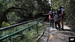 Archivo - Una familia, usando mascarillas, camina por un sendero en el zoológico en las afueras de Quito, Ecuador, el 8 de julio de 2020.