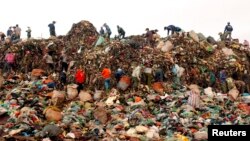FILE - Scavengers search for recyclable materials to be sold to recycling centers, at the Nam Son garbage dump, north of Hanoi, Vietnam.