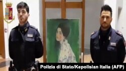 Polisi berdiri di dekat sebuah lukisan "Portrait of a Woman" karya pelukis Austria Gustav Klimt. Lukisan tersebut ditemukan setelah dicuri lebih dari 20 tahun. (Foto: AFP/Polizia di Stato/Kepolisian Italia)