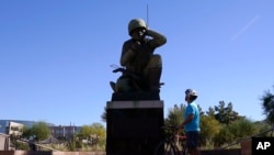 A visitor looks up at the Navajo Code Talkers Memorial on Veterans Day, Nov. 11, 2020, in Phoenix, Arizona. John Kinsel Sr., one of the last remaining Navajo Code Talkers who transmitted messages during World War II based on the tribe's native language, has died at 107. 