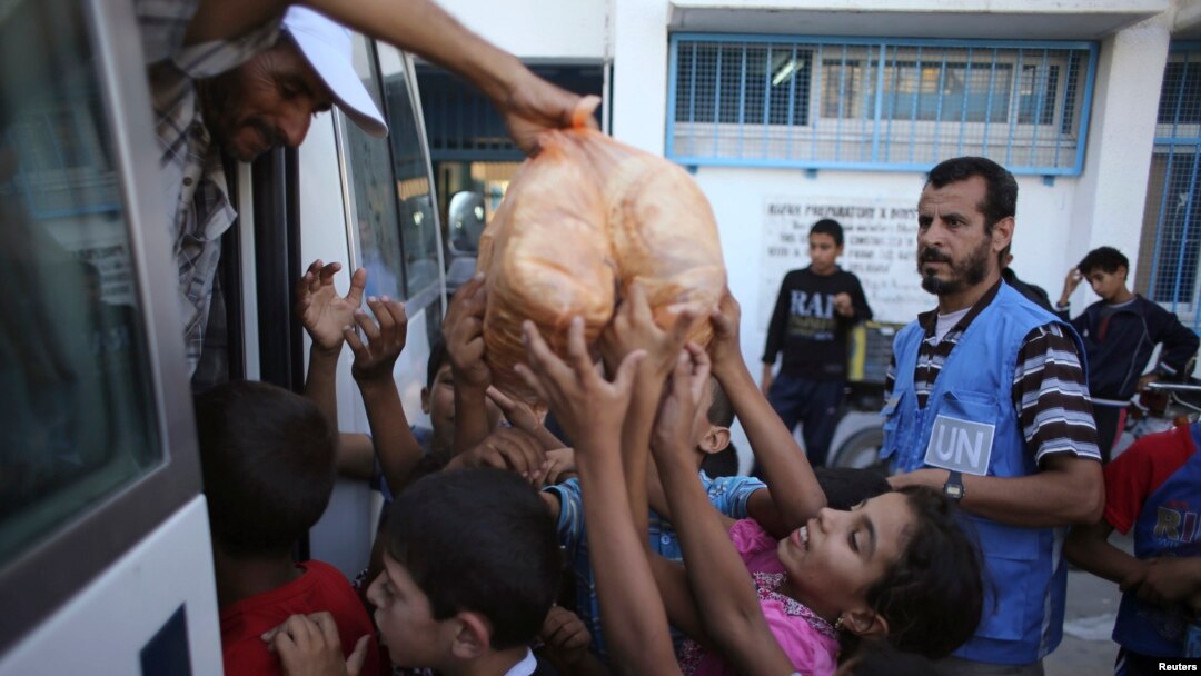 Palestinian children receive bags of bread from United Nations workers at a U.N.-run school in Rafah in the southern Gaza Strip July 19, 2014.