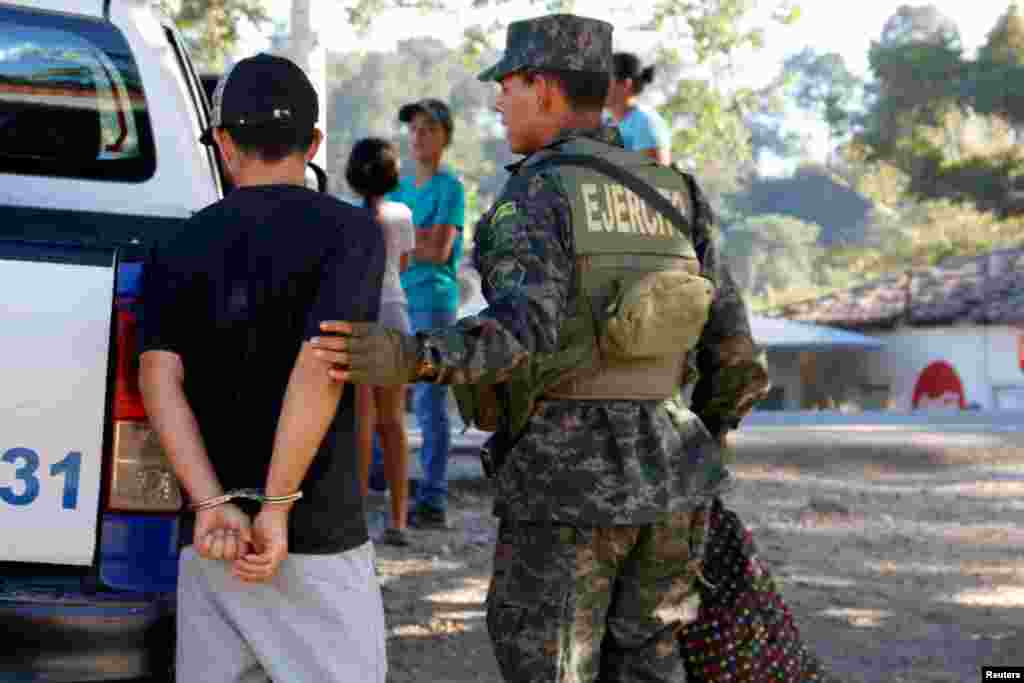 Un oficial de la policía militar detiene a un hombre que viaja con la caravana de migrantes, debido a una orden de arresto, en un punto de control en San Marcos.