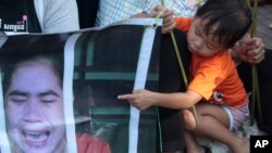 A child of Boeung Kak lake community's land activists points a poster of detained Tep Vanny in front of the appeals court in Phnom Penh, Cambodia, Tuesday, Aug. 8, 2017. The court upheld a 2 ½ year prison term against Tep Vanny, a prominent land rights activist on charges of committing violence at a protest she helped lead outside of Prime Minister Hun Sen's residence more than three years ago. (AP Photo/Heng Sinith)