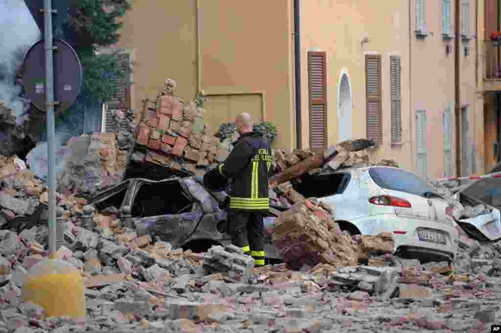 An Italian firefighter stands among rubble and destroyed cars in Modena, Italy, May 20, 2012.