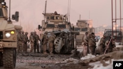 U.S. soldiers search the site where a suicide attacker rammed a car bomb into a NATO convoy, killing two foreign civilian contractors, in the Afghan capital Kabul, Afghanistan, Feb. 10, 2014. 