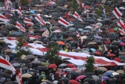 People take cover from rain under umbrellas during an opposition rally to protest against police brutality and to reject the presidential election results in Minsk, Belarus, Sept. 6, 2020.