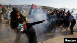 An Israeli soldier detains a Palestinian woman during a protest calling for the opening an Israeli-closed gate leading to Nabi Saleh village, near the West Bank city of Ramallah April 14, 2014.