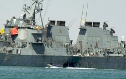 FILE - In this Oct. 15, 2000 file photo, experts in a speed boat examine the damaged hull of the USS Cole at the Yemeni port of Aden after an al-Qaida attack that killed 17 sailors.