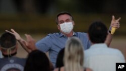 El presidente de Brasil, Jair Bolsonaro, quien tres veces positivo al COVID-19, habla con sus partidarios, frente a su residencia oficial, el Palacio Alvorada, el viernes 24 de julio de 2020.