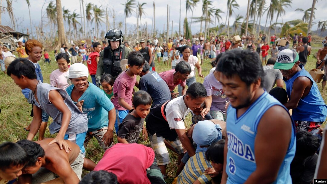 Para penyintas topan Haiyan bergegas mengambil bantuan air segar yang dikirimkan oleh helikopter militer AS ke desa mereka yang terisolasi di sebelah utara Tacloban (17/11).