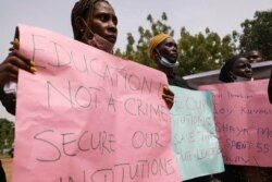 Parents and relatives of students from the Federal College of Forestry Mechanization in Kaduna who have been abducted, hold placards during a demonstration in Abuja on May 4, 2021.