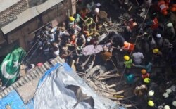 Rescuers carry the body of a victim at the site of a building that collapsed in Mumbai, India, Tuesday, July 16, 2019.
